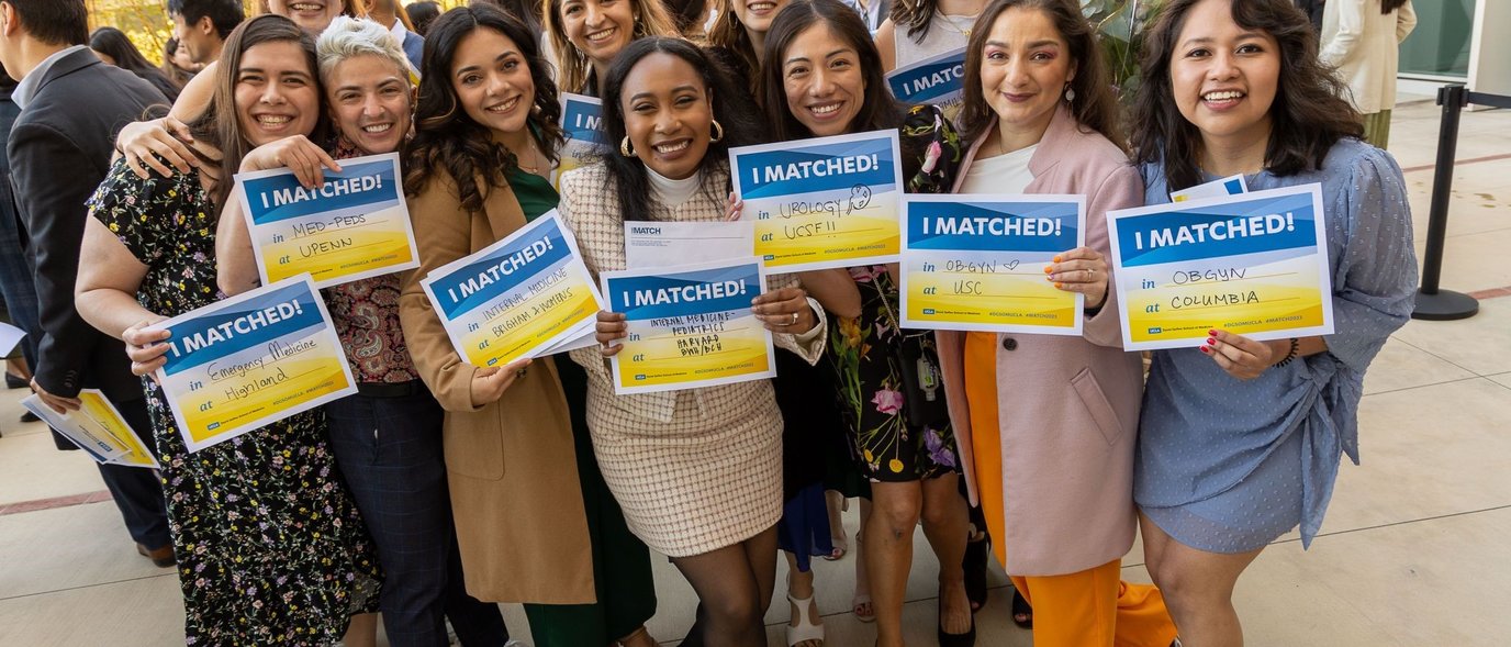 Photo of medical school students holding up signs with their residency match locations